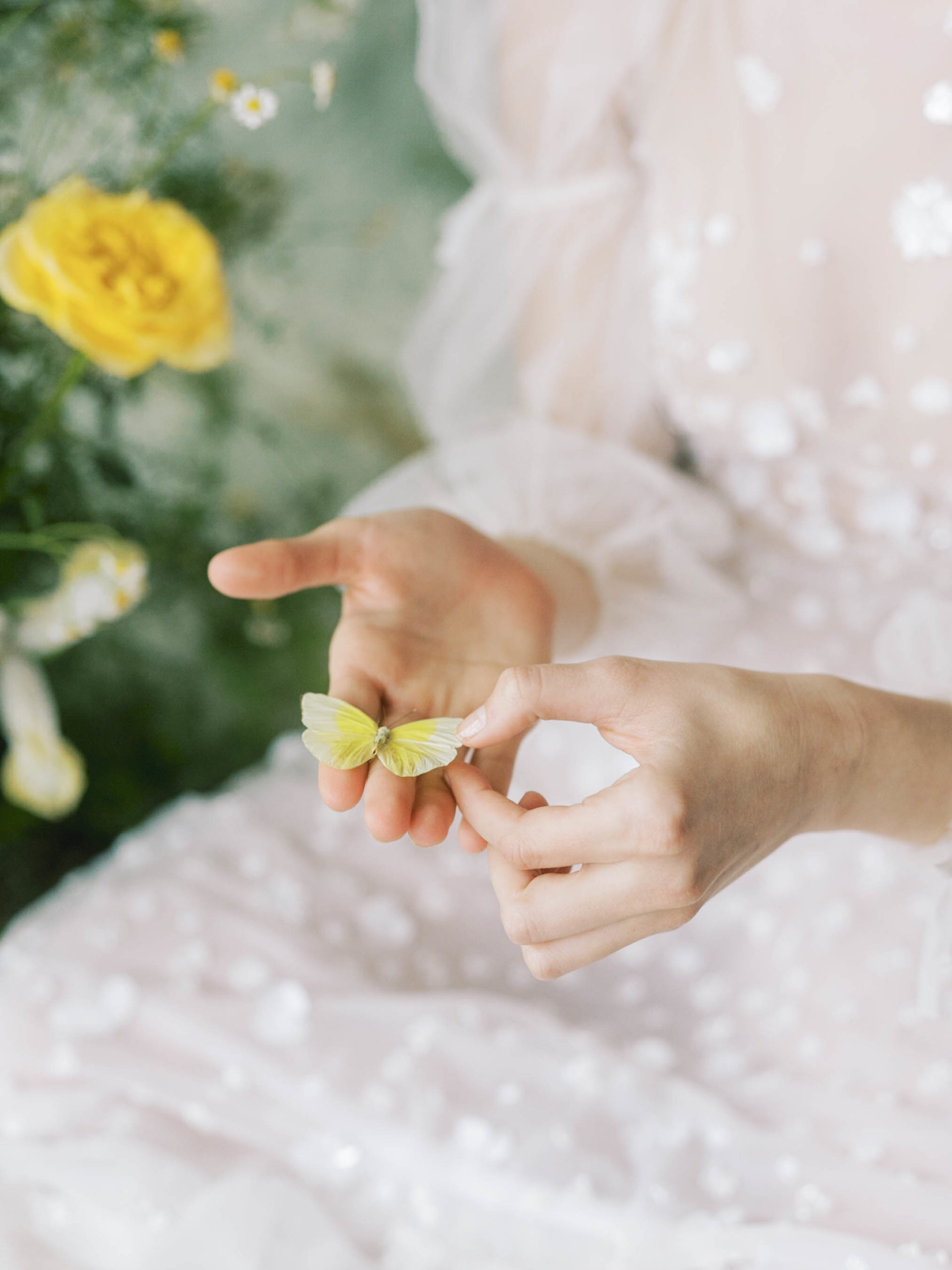bride holding yellow butterfly in floral detailed dress 